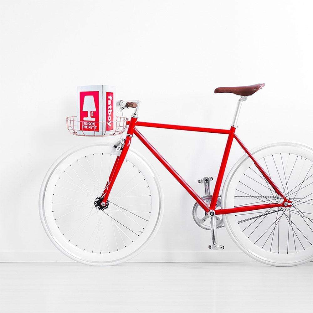 
                  
                    Shot of a white bike against a white wall. The basket has a box that reads Fatboy.
                  
                